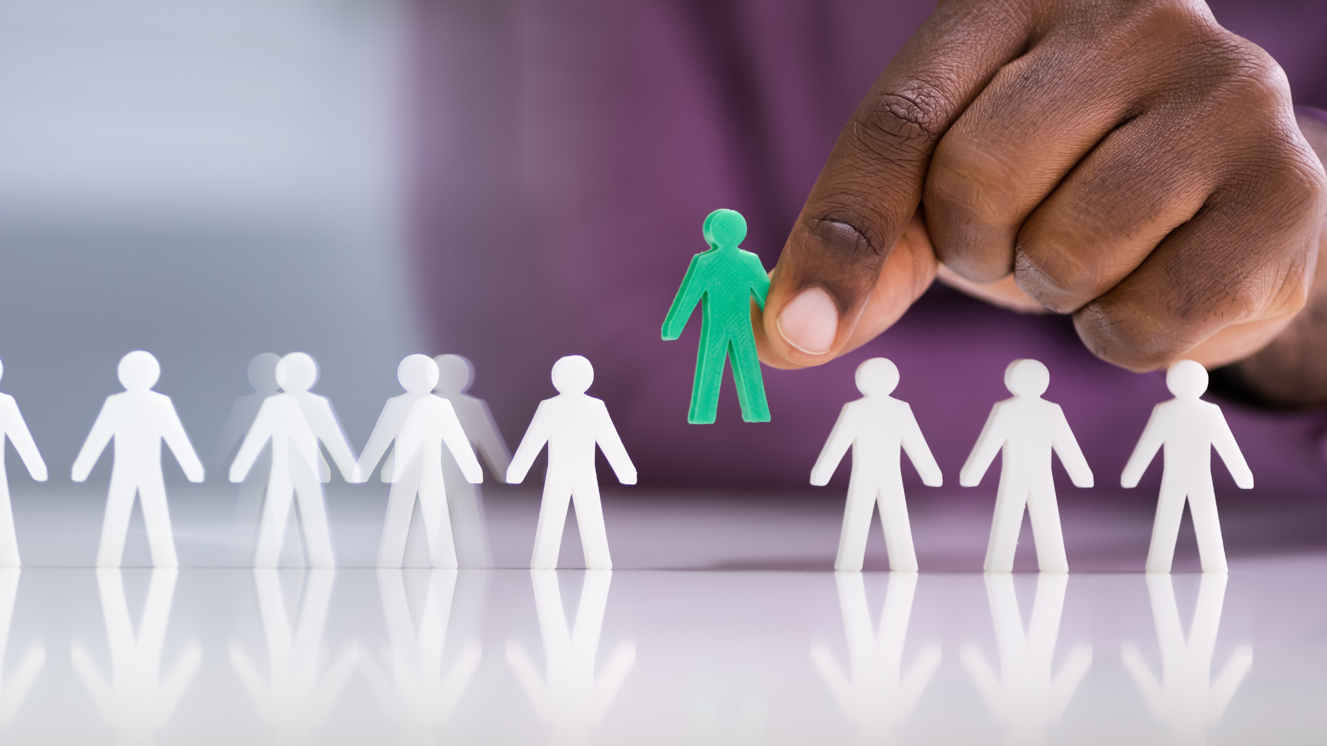 Hand selecting a unique figure from a line, representing Unbound's focus on independent candidates.